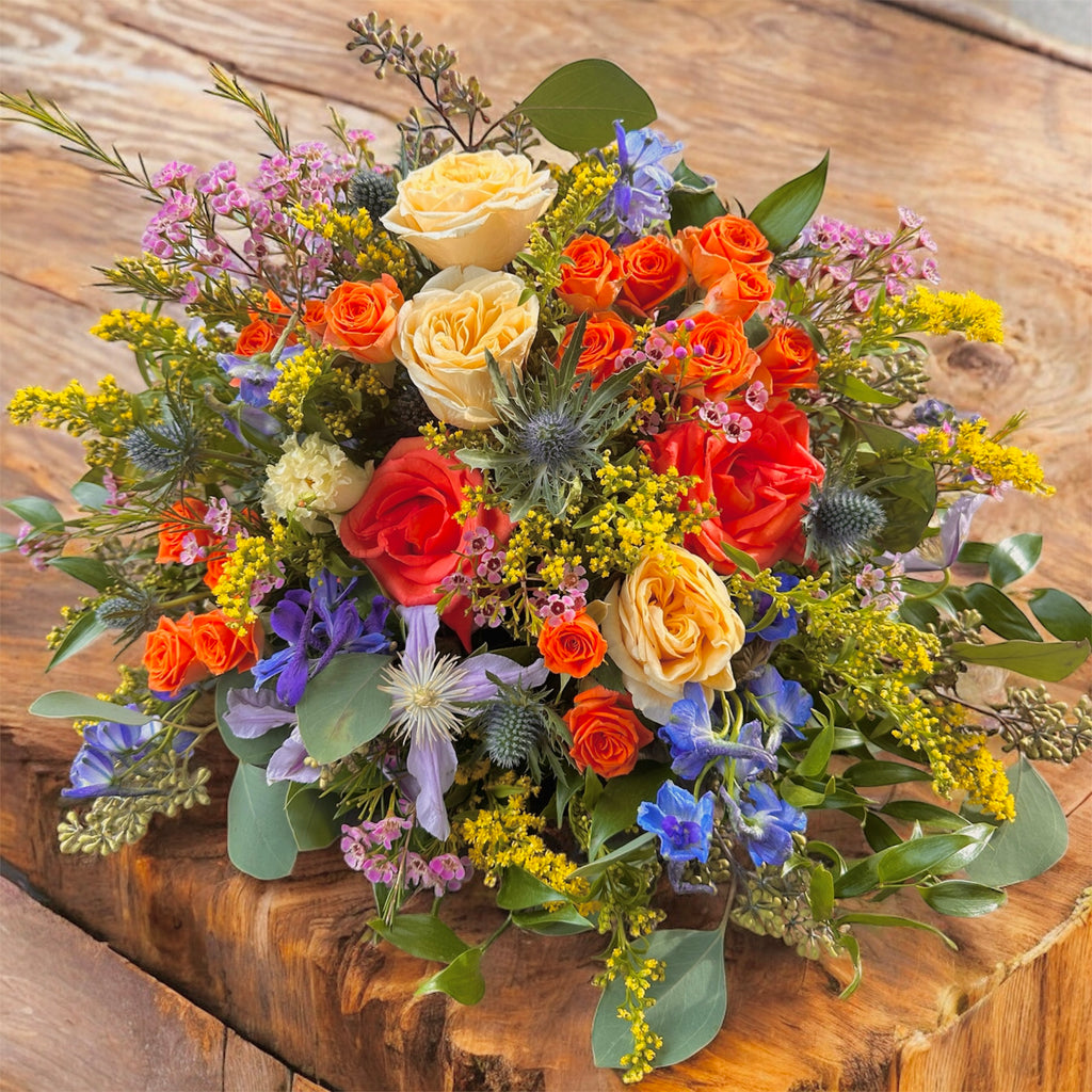 Colourful Funeral posy in shades of orange, yellows and blues