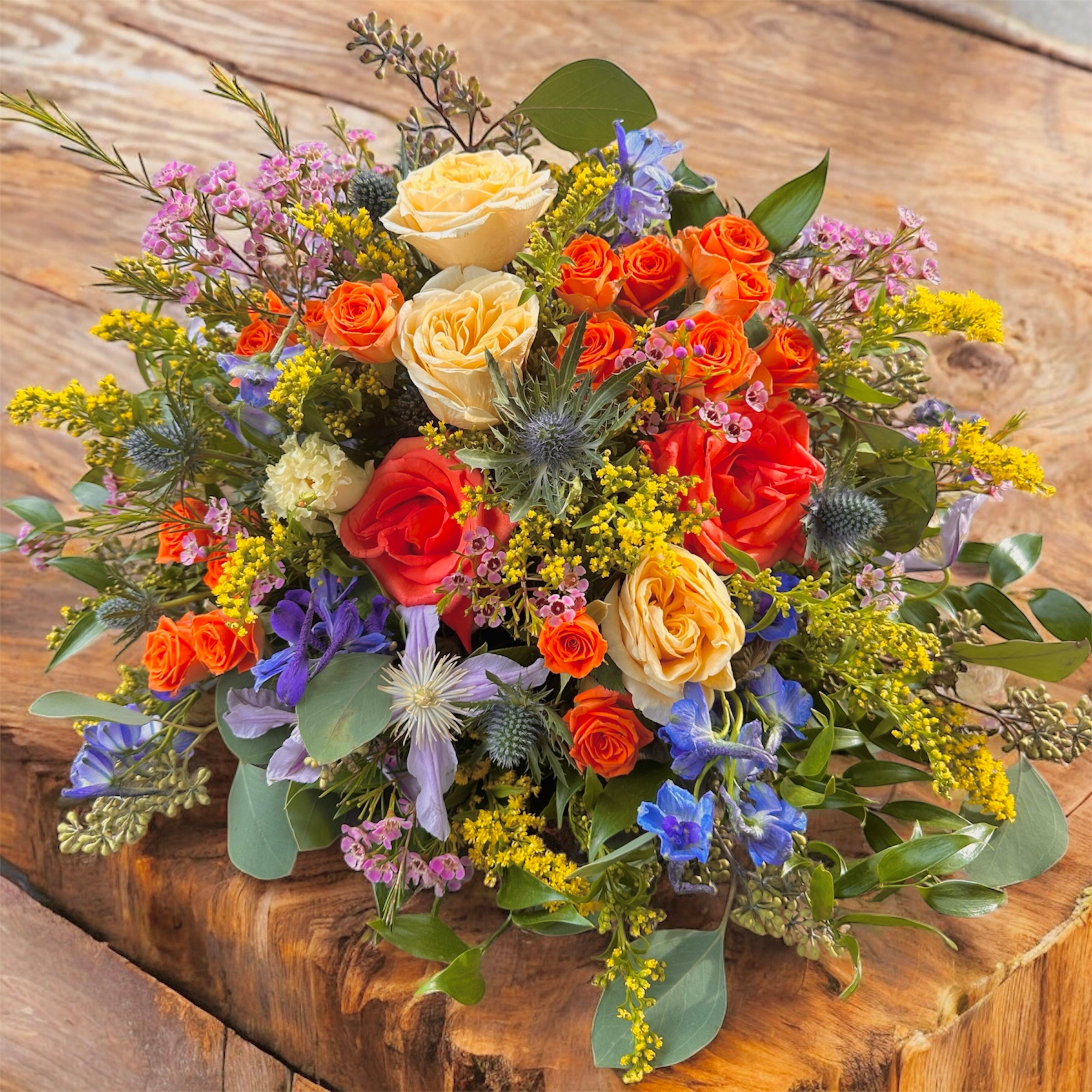 Colourful Funeral posy in shades of orange, yellows and blues