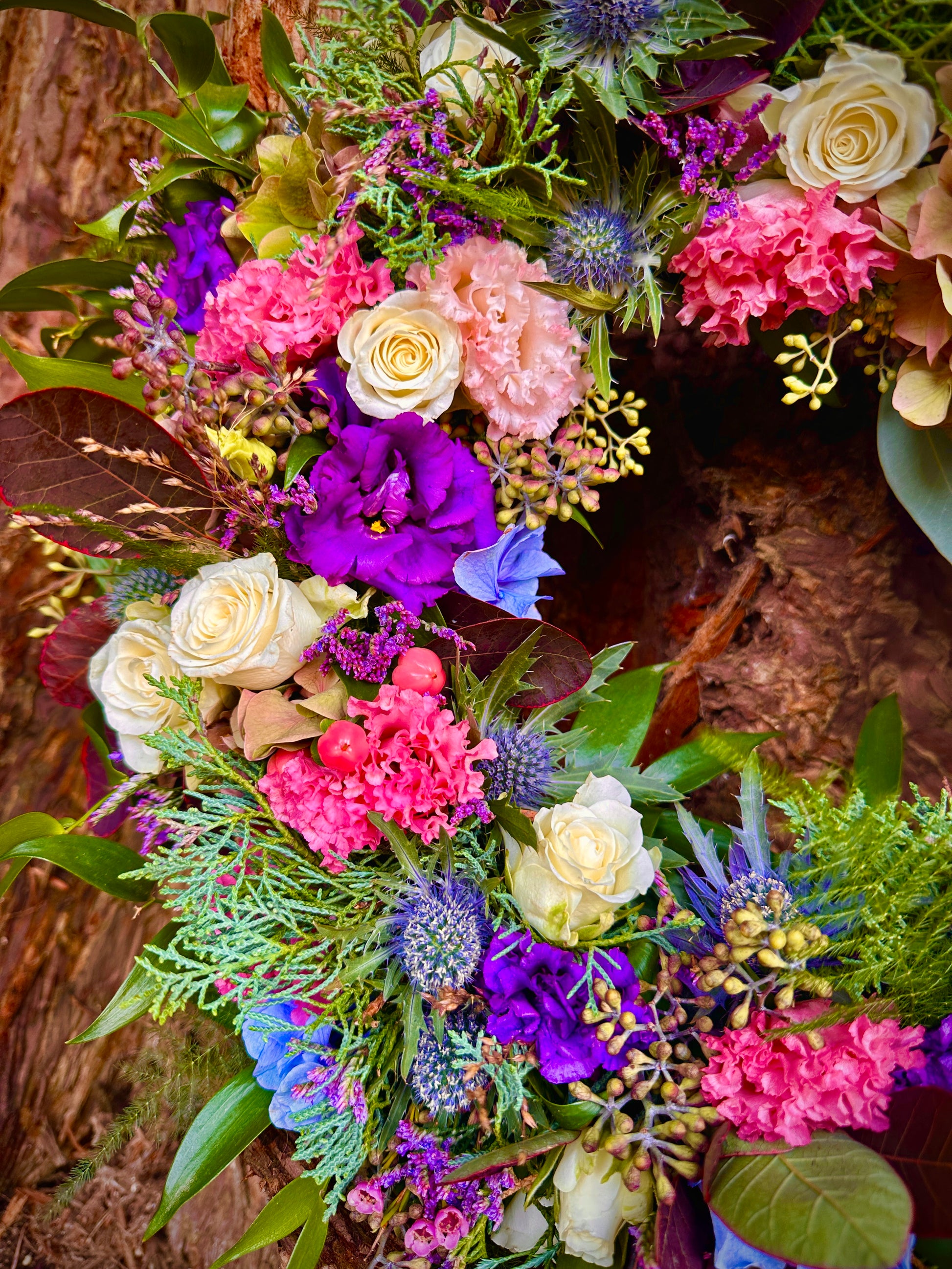 pink, purple, blue and white flowers in a wreath shape 