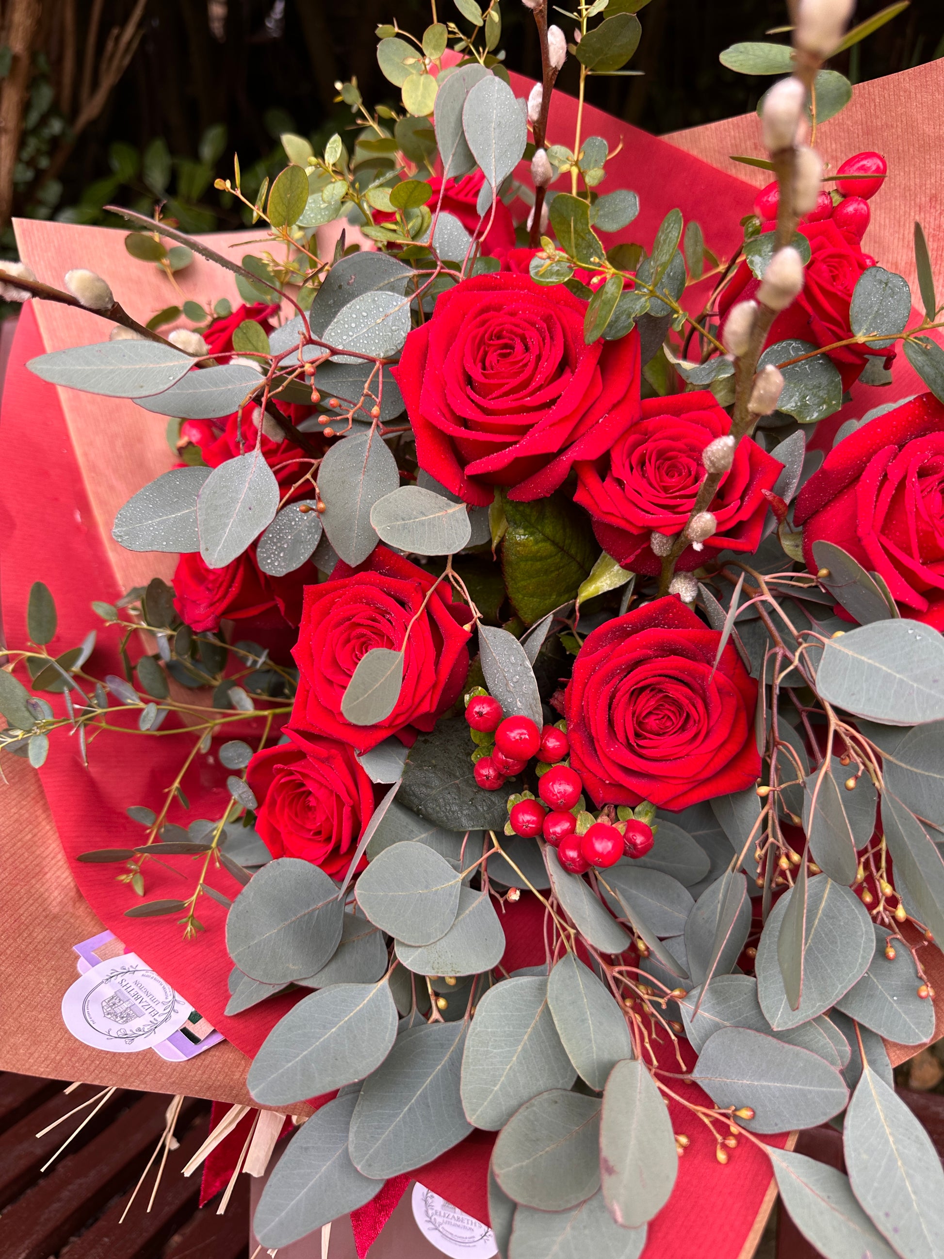 Bouquet of red roses with greenery on a red box