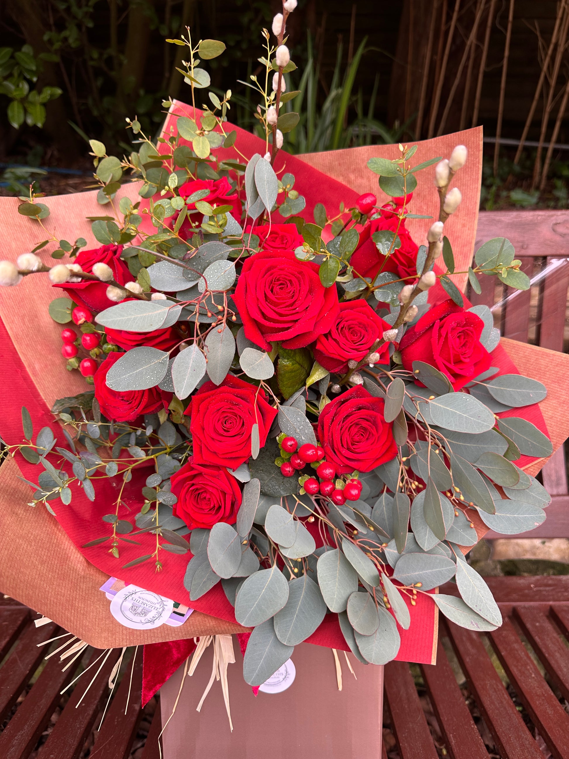 Bouquet of red roses with greenery on a wooden chair