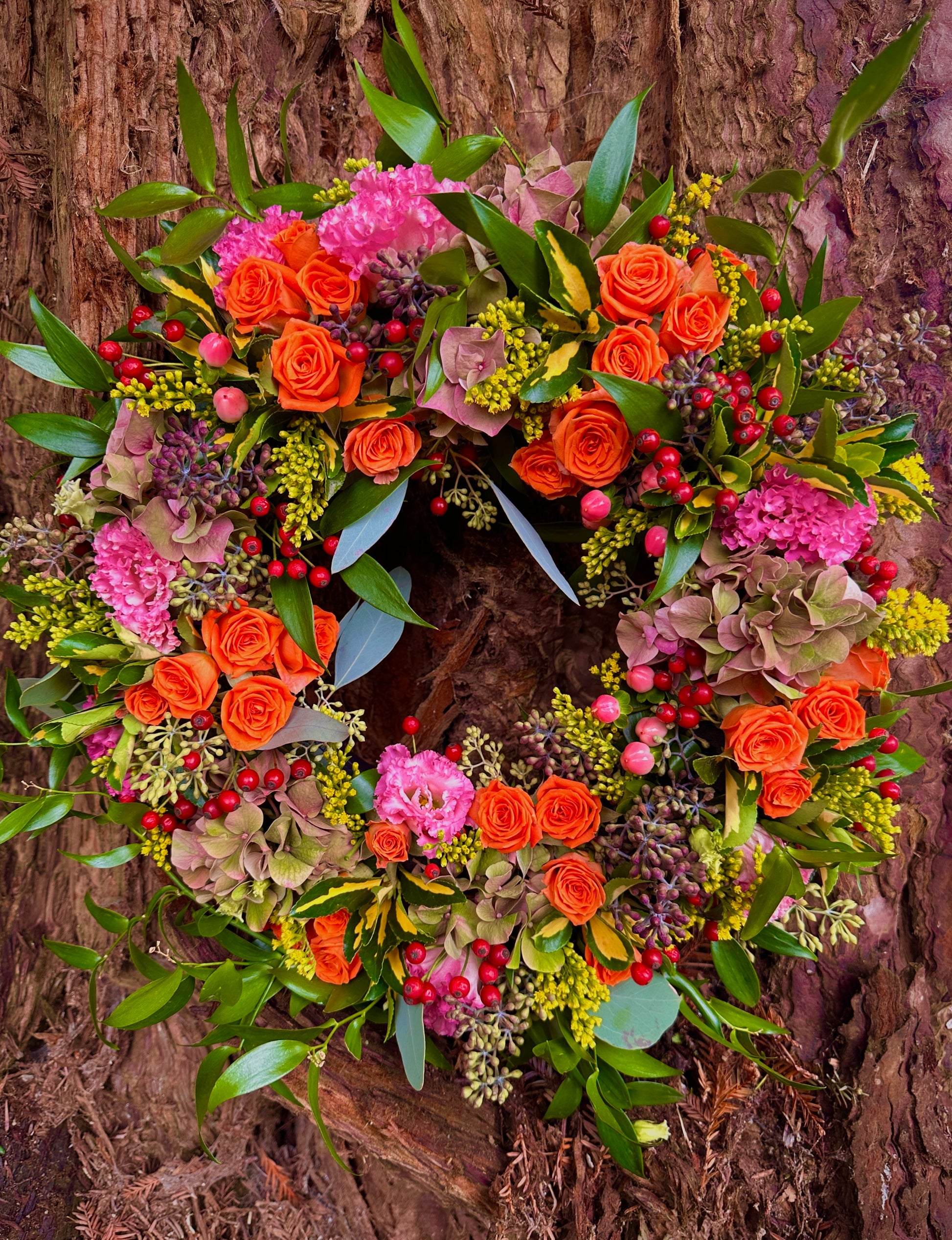 Colourful floral wreath with orange, pink, and green foliage