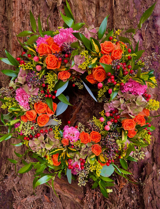 Colourful floral wreath with orange, pink, and green foliage